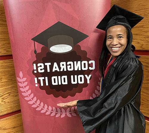 SNU Graduate, Lauren Morrison-Edwards, standing next to sign that says "Congrats, you did it!"